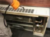 A maintenance worker in orange gloves is using a cleaning tool to service a dirty fan coil unit.